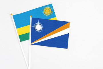Marshall Islands and Rwanda stick flags on white background. High quality fabric, miniature national flag. Peaceful global concept.White floor for copy space.