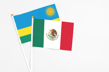 Mexico and Rwanda stick flags on white background. High quality fabric, miniature national flag. Peaceful global concept.White floor for copy space.