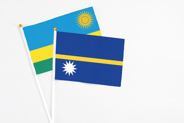 Nauru and Rwanda stick flags on white background. High quality fabric, miniature national flag. Peaceful global concept.White floor for copy space.