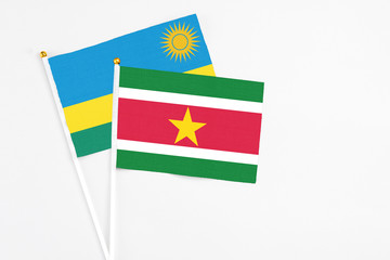 Obraz premium Suriname and Rwanda stick flags on white background. High quality fabric, miniature national flag. Peaceful global concept.White floor for copy space.