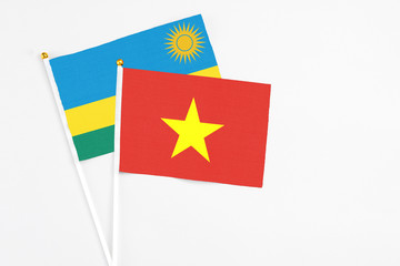 Vietnam and Rwanda stick flags on white background. High quality fabric, miniature national flag. Peaceful global concept.White floor for copy space.