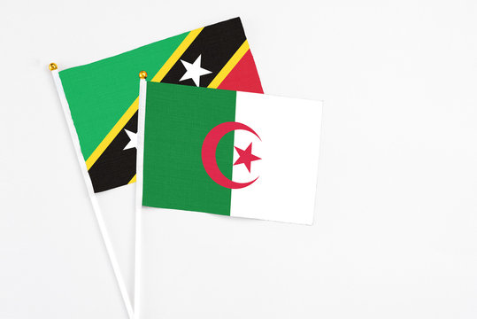Algeria and Saint Kitts And Nevis stick flags on white background. High quality fabric, miniature national flag. Peaceful global concept.White floor for copy space.