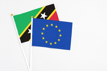 European Union and Saint Kitts And Nevis stick flags on white background. High quality fabric, miniature national flag. Peaceful global concept.White floor for copy space.