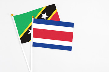 Costa Rica and Saint Kitts And Nevis stick flags on white background. High quality fabric, miniature national flag. Peaceful global concept.White floor for copy space.