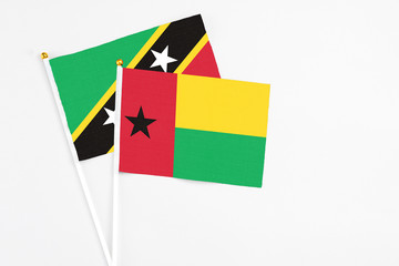 Guinea Bissau and Saint Kitts And Nevis stick flags on white background. High quality fabric, miniature national flag. Peaceful global concept.White floor for copy space.