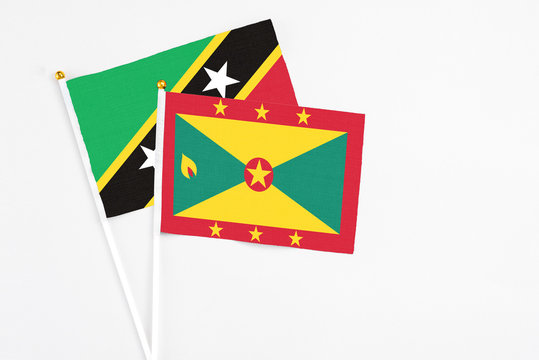Grenada and Saint Kitts And Nevis stick flags on white background. High quality fabric, miniature national flag. Peaceful global concept.White floor for copy space.