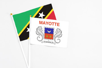Mayotte and Saint Kitts And Nevis stick flags on white background. High quality fabric, miniature national flag. Peaceful global concept.White floor for copy space.