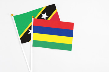 Mauritius and Saint Kitts And Nevis stick flags on white background. High quality fabric, miniature national flag. Peaceful global concept.White floor for copy space.
