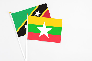 Myanmar and Saint Kitts And Nevis stick flags on white background. High quality fabric, miniature national flag. Peaceful global concept.White floor for copy space.