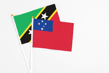 Samoa and Saint Kitts And Nevis stick flags on white background. High quality fabric, miniature national flag. Peaceful global concept.White floor for copy space.