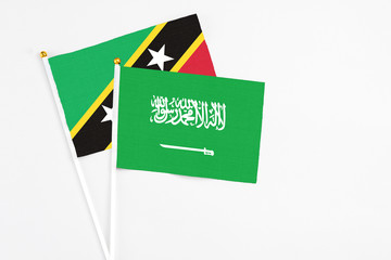 Saudi Arabia and Saint Kitts And Nevis stick flags on white background. High quality fabric, miniature national flag. Peaceful global concept.White floor for copy space.