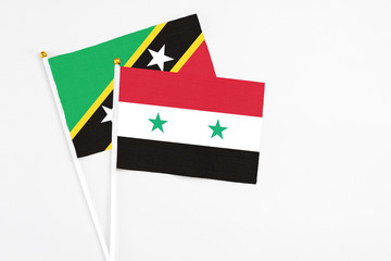 Syria and Saint Kitts And Nevis stick flags on white background. High quality fabric, miniature national flag. Peaceful global concept.White floor for copy space.