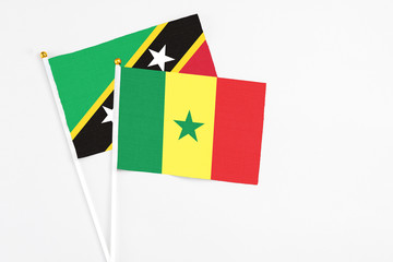 Senegal and Saint Kitts And Nevis stick flags on white background. High quality fabric, miniature national flag. Peaceful global concept.White floor for copy space.