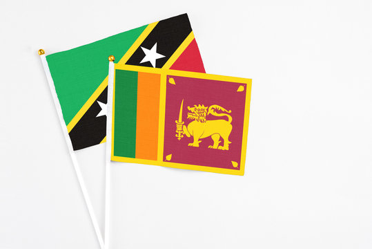 Sri Lanka and Saint Kitts And Nevis stick flags on white background. High quality fabric, miniature national flag. Peaceful global concept.White floor for copy space.