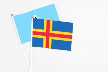 Aland Islands and Saint Lucia stick flags on white background. High quality fabric, miniature national flag. Peaceful global concept.White floor for copy space.