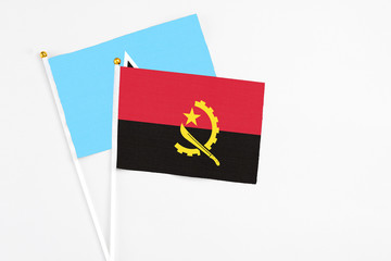 Angola and Saint Lucia stick flags on white background. High quality fabric, miniature national flag. Peaceful global concept.White floor for copy space.
