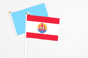 French Polynesia and Saint Lucia stick flags on white background. High quality fabric, miniature national flag. Peaceful global concept.White floor for copy space.