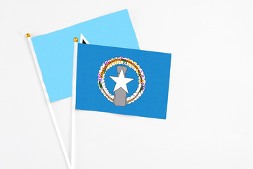 Northern Mariana Islands and Saint Lucia stick flags on white background. High quality fabric, miniature national flag. Peaceful global concept.White floor for copy space.