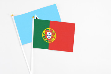 Portugal and Saint Lucia stick flags on white background. High quality fabric, miniature national flag. Peaceful global concept.White floor for copy space.
