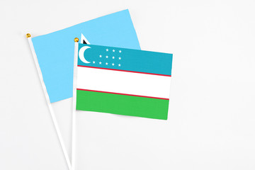 Uzbekistan and Saint Lucia stick flags on white background. High quality fabric, miniature national flag. Peaceful global concept.White floor for copy space.