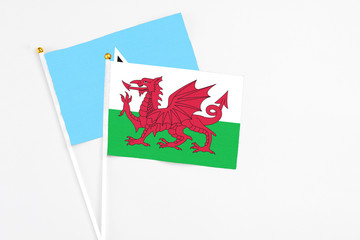 Wales and Saint Lucia stick flags on white background. High quality fabric, miniature national flag. Peaceful global concept.White floor for copy space.