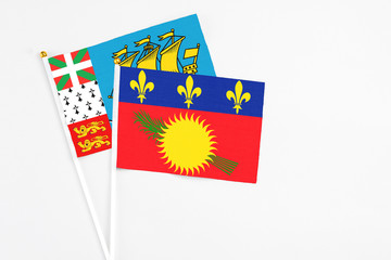 Guadeloupe and Saint Pierre And Miquelon stick flags on white background. High quality fabric, miniature national flag. Peaceful global concept.White floor for copy space.