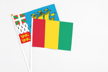 Guinea and Saint Pierre And Miquelon stick flags on white background. High quality fabric, miniature national flag. Peaceful global concept.White floor for copy space.