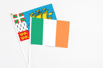 Ireland and Saint Pierre And Miquelon stick flags on white background. High quality fabric, miniature national flag. Peaceful global concept.White floor for copy space.