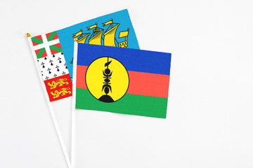 New Caledonia and Saint Pierre And Miquelon stick flags on white background. High quality fabric, miniature national flag. Peaceful global concept.White floor for copy space.