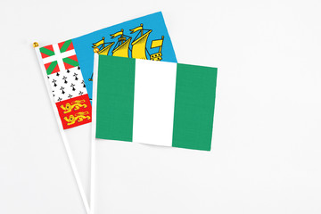 Nigeria and Saint Pierre And Miquelon stick flags on white background. High quality fabric, miniature national flag. Peaceful global concept.White floor for copy space.