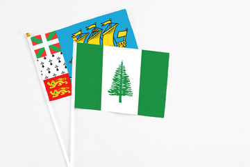 Norfolk Island and Saint Pierre And Miquelon stick flags on white background. High quality fabric, miniature national flag. Peaceful global concept.White floor for copy space.