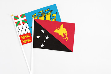 Papua New Guinea and Saint Pierre And Miquelon stick flags on white background. High quality fabric, miniature national flag. Peaceful global concept.White floor for copy space.