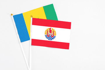 French Polynesia and Saint Vincent And The Grenadines stick flags on white background. High quality fabric, miniature national flag. Peaceful global concept.White floor for copy space.