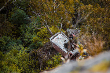 Car wreckage at bottom of hill in national park forest