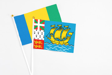 Saint Pierre And Miquelon and Saint Vincent And The Grenadines stick flags on white background. High quality fabric, miniature national flag. Peaceful global concept.White floor for copy space.