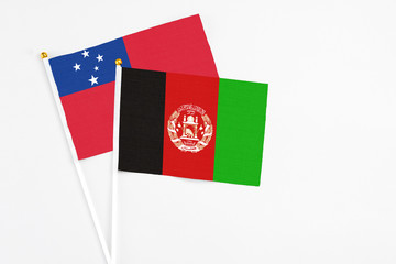 Afghanistan and Samoa stick flags on white background. High quality fabric, miniature national flag. Peaceful global concept.White floor for copy space.