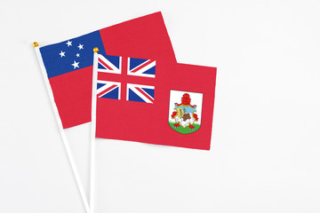 Fototapeta premium Bermuda and Samoa stick flags on white background. High quality fabric, miniature national flag. Peaceful global concept.White floor for copy space.