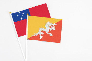 Bhutan and Samoa stick flags on white background. High quality fabric, miniature national flag. Peaceful global concept.White floor for copy space.