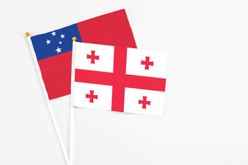 Georgia and Samoa stick flags on white background. High quality fabric, miniature national flag. Peaceful global concept.White floor for copy space.