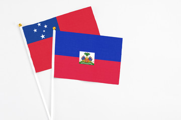 Haiti and Samoa stick flags on white background. High quality fabric, miniature national flag. Peaceful global concept.White floor for copy space.