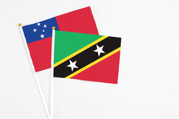 Fototapeta premium Saint Kitts And Nevis and Samoa stick flags on white background. High quality fabric, miniature national flag. Peaceful global concept.White floor for copy space.