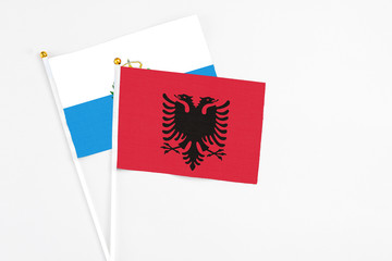 Albania and San Marino stick flags on white background. High quality fabric, miniature national flag. Peaceful global concept.White floor for copy space.
