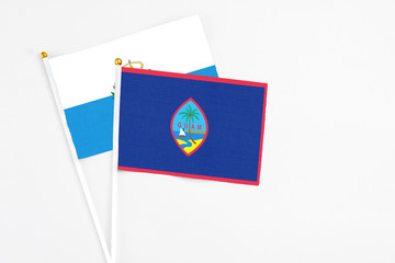 Guam and San Marino stick flags on white background. High quality fabric, miniature national flag. Peaceful global concept.White floor for copy space.