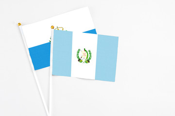 Guatemala and San Marino stick flags on white background. High quality fabric, miniature national flag. Peaceful global concept.White floor for copy space.