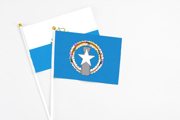 Northern Mariana Islands and San Marino stick flags on white background. High quality fabric, miniature national flag. Peaceful global concept.White floor for copy space.