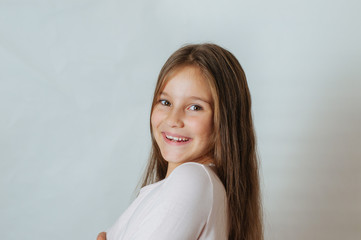 Little pretty girl age 6-7 years with very long hair expresses emotional joy and a smile on a white background