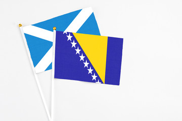 Bosnia Herzegovina and Scotland stick flags on white background. High quality fabric, miniature national flag. Peaceful global concept.White floor for copy space.