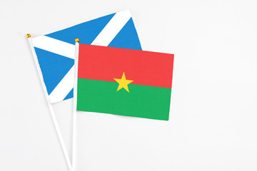 Burkina Faso and Scotland stick flags on white background. High quality fabric, miniature national flag. Peaceful global concept.White floor for copy space.