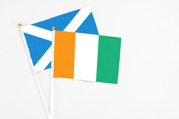 Cote D'Ivoire and Scotland stick flags on white background. High quality fabric, miniature national flag. Peaceful global concept.White floor for copy space.