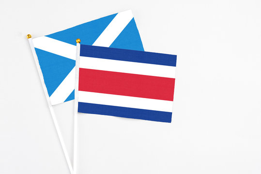 Costa Rica and Scotland stick flags on white background. High quality fabric, miniature national flag. Peaceful global concept.White floor for copy space.